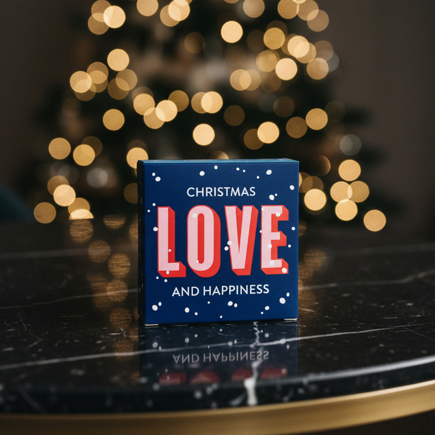 Seifenverpackung in Blau- und Rottönen mit Aufschrift Christmas Love and Happiness vor weihnachtlichem Hintergrund - eine kleine sinnvolle Aufmerksamkeit zu Weihnachten
