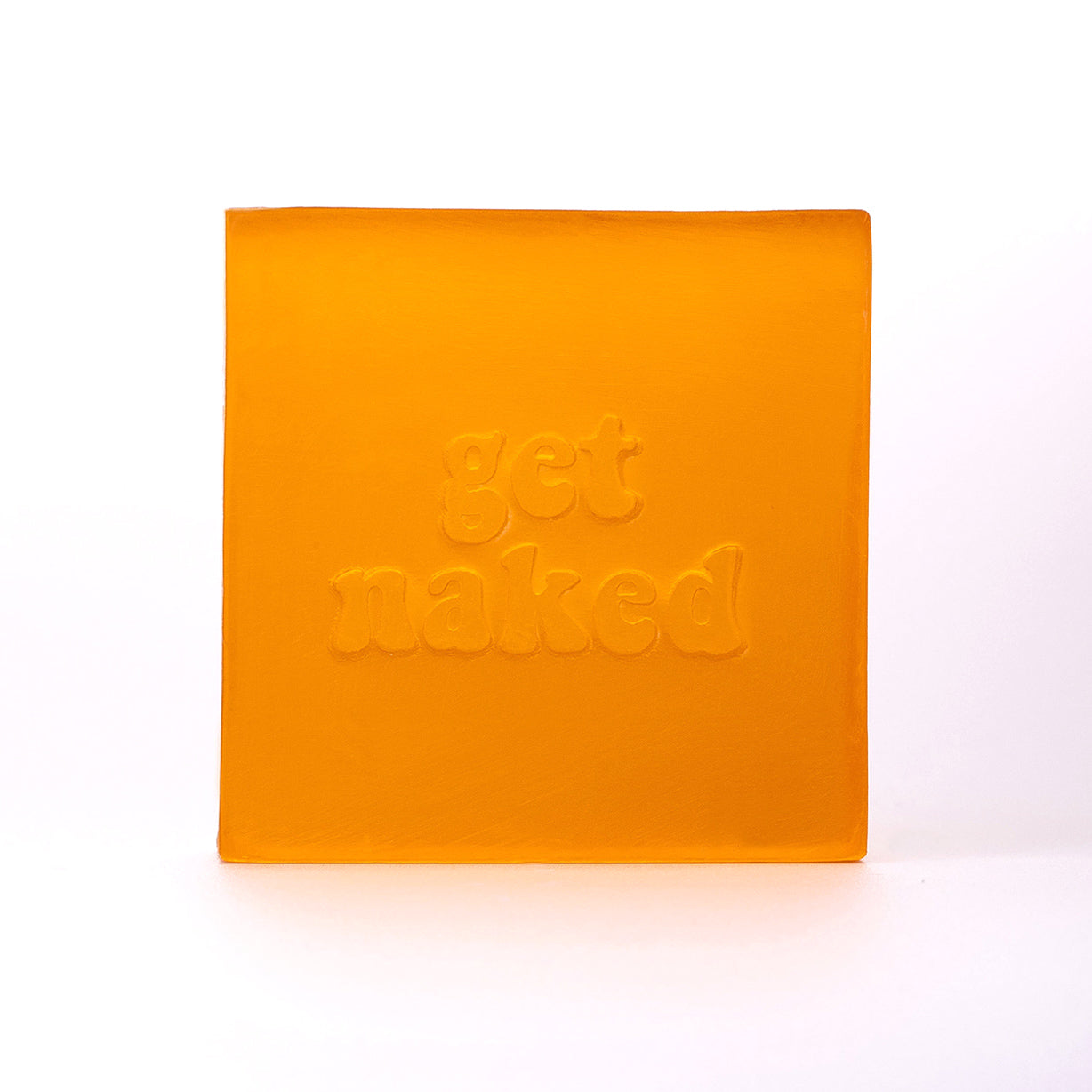 quadratische transparente Glycerinseife in orange mit einer Stempelung "get naked", hier von vorne zu sehen