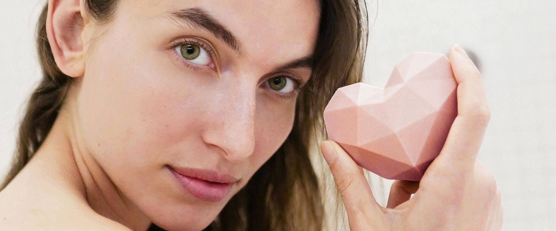 junge Frau hält eine rosafarbene Seife in Herzform in der Hand